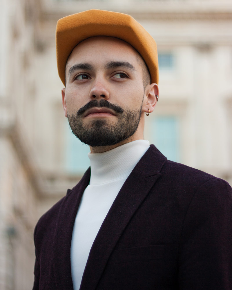 Portrait of Jon Jacobsen, creative director and career coach, wearing a polygonal hat and looking optimistically to the future.